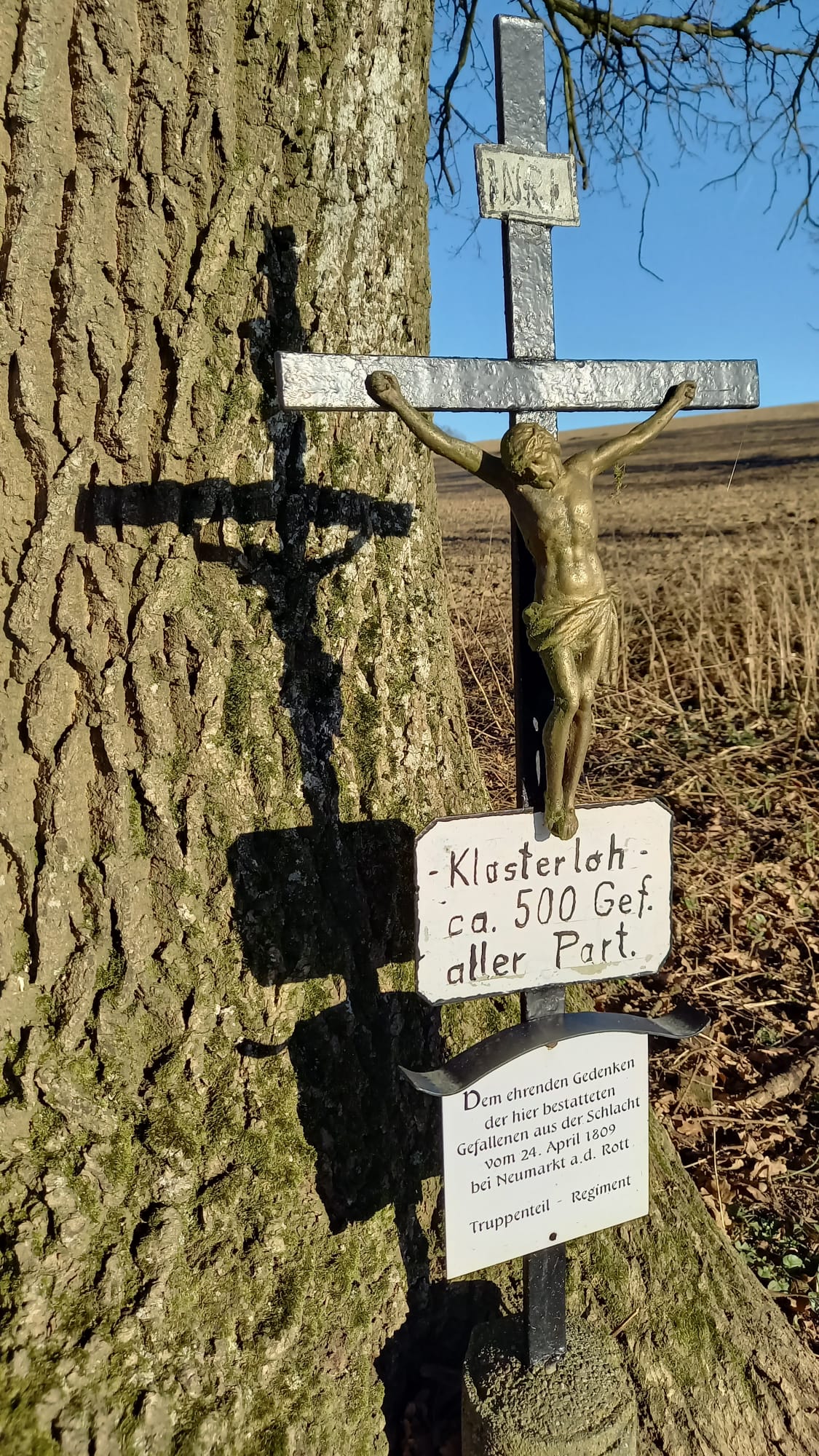 Ein Neuner-Kreuz mit einer Aufschrift, dass sich hier ein Massengrab mit 500 gefallenen Soldaten befindet.
